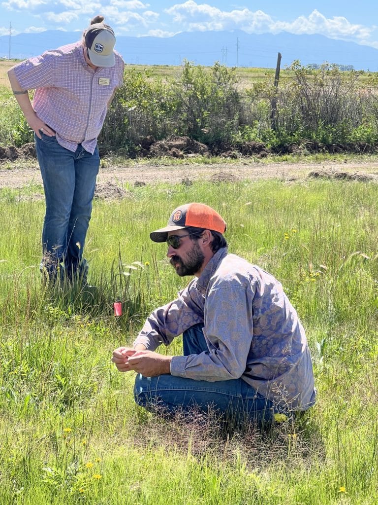 Sam Schmidt kneels in the grass of a field at San Juan Ranch.