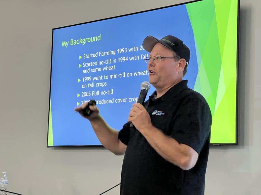 Kansas farmer Brice Custer stands in front of his presentation screen with a microphone.