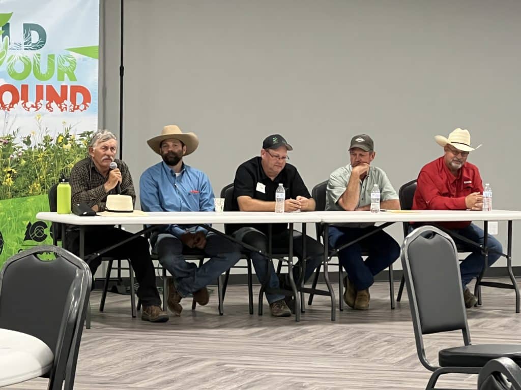 A panel of five farmers faces the crowd while discussing soil health.
