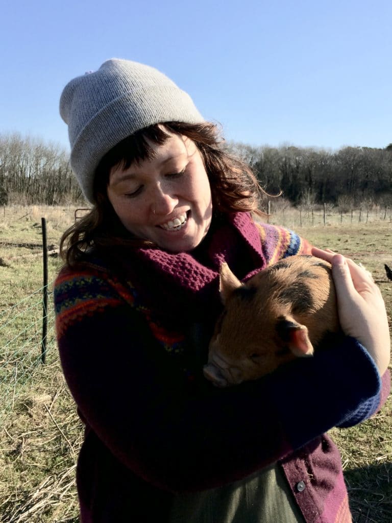 Natalie McGill cradles a Kunekune piglet in the pasture at Perennial Roots Farm, Accomac, Virginia.