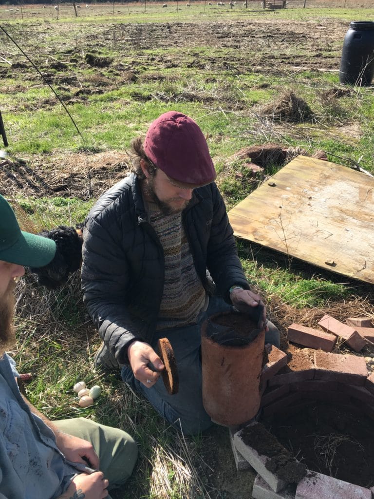Farmer Stewart Lundy opens a terra cotta canister of overwintered plaintain to show farm apprentice Austin Pearle-Ojala at Perennial Roots Farm, Accomac, Virginia.