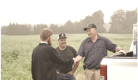 Three farmers shaking hands in a field